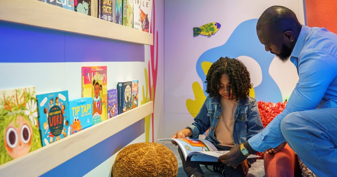 A child and parent reading a book inside a British Library exhibition