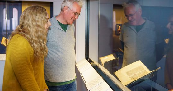 A man and a woman stood looking at a display cabinet in an exhibition at the British Library