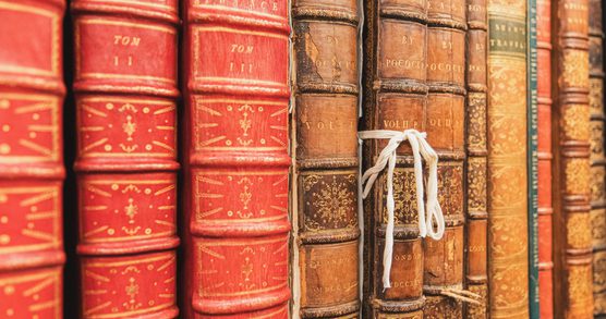 Spines of books on a shelf. One book has a white cotton ribbon around it