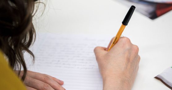 A hand writing on lined paper.