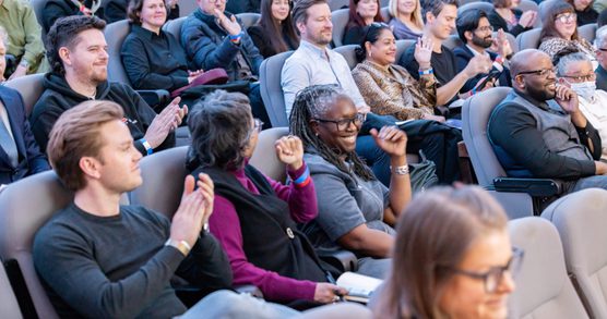 people smiling and clapping in the audience at an event