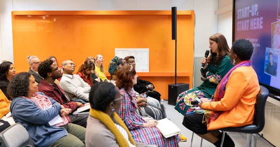 Two people speak to a small audience of event attendees.