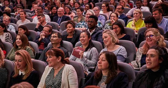 People in an audience smiling.