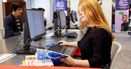 A business woman sits and consults resources at a Business & IP Centre in Bristol.