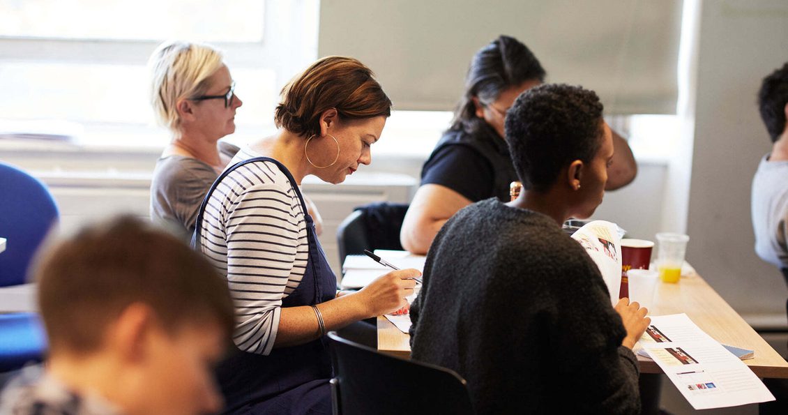 Image of a group of people in a room taking notes.