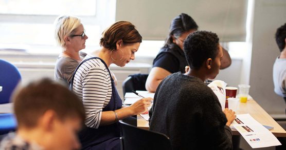 Image of a group of people in a room taking notes.