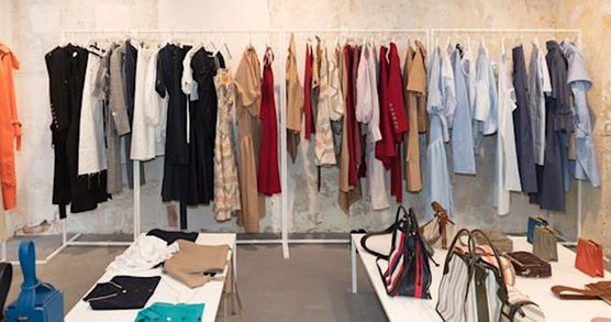 Shop interior. Clothing displayed on tables and on clothes racks