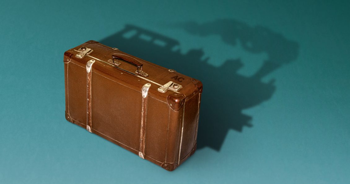 A brown suitcase sits on a teal background. A shadow forms the silhouette of a stream train behind the suitcase, creating a visual metaphor for mystery writing and travel.