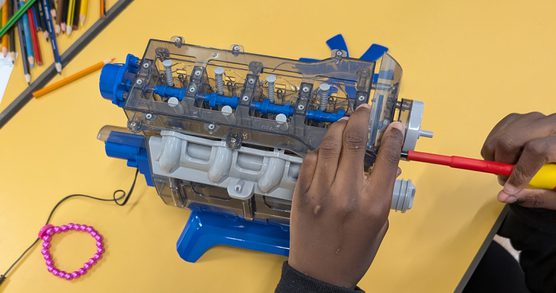 A child’s hands using a screwdriver to repair an electronic toy.