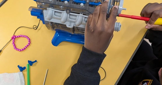 A child’s hands using a screwdriver to repair an electronic toy.