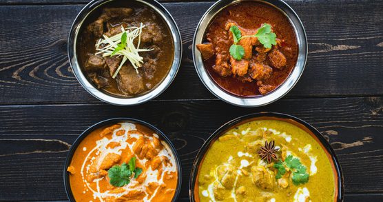 Bowls of Indian curries on a wooden table
