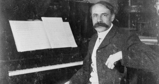Black and white photograph of Edward Elgar seated at the piano.