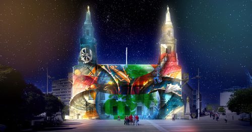 A group of people standing in front of a building with a projection of Earth, hot air balloons, planets and a telescope on its façade.
