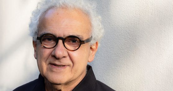 Portrait of Milton Hatoum seated against a neutral background, looking slightly to the side