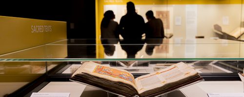 An Ethiopian Bible in a glass case, with silhouettes of three visitors in the background