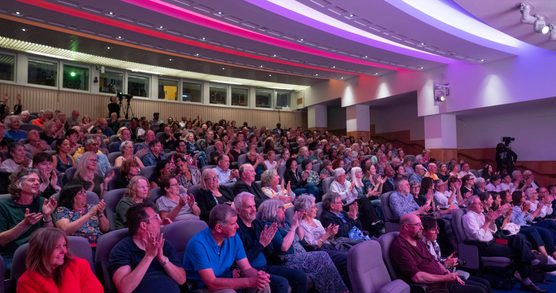 An audience sitting on tiered seating, they are smiling and applauding