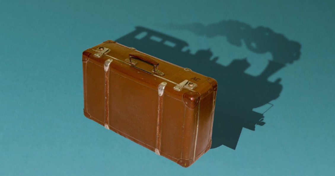 Illustration of a old fashioned brown suitcase, the shadow it casts show a steam train engine