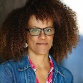 Photo of Bernardine Evaristo, wearing a denim jacket and glasses