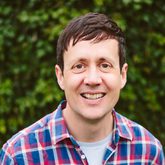 Photo of Patrick Barkham, smiling at camera and wearing a blue, red and white checked short-sleeved shirt