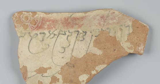 A piece of stone with pattern and script wearing away.