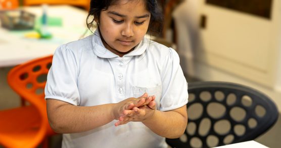 A young girl making a small book in one of our school workshops