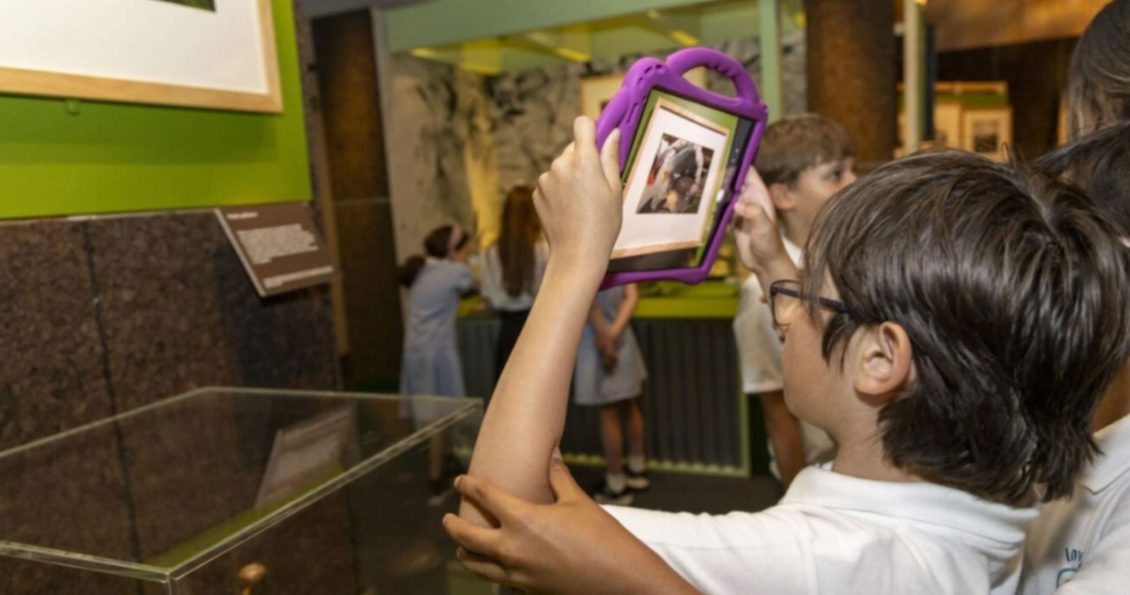 A child holding up a tablet in a pink frame