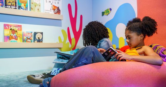 Children reading books in our the reading corner of the Story Explorers exhibition at the British Library