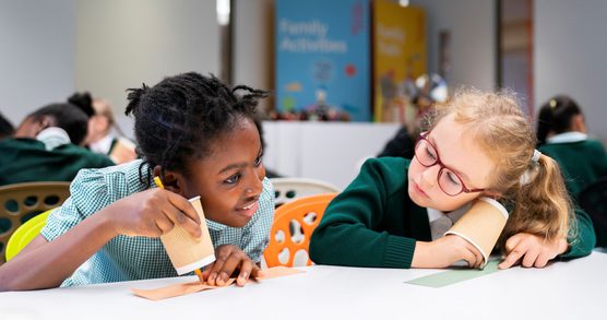 Two children listening to sounds via an activity with paper cups