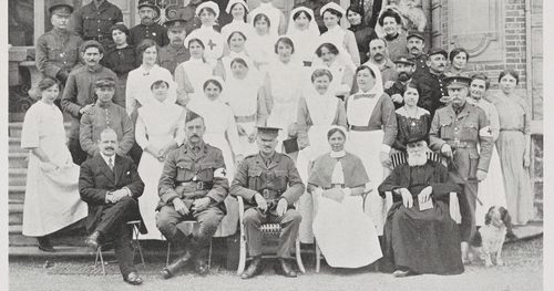 A formal black and white portrait photograph from 1915-1916 showing women in nursing attire and men in military uniform