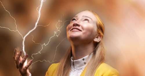 Photo of A F Steadman in a yellow jacket, the photo has been edited to look as if lightening is coming off her hand