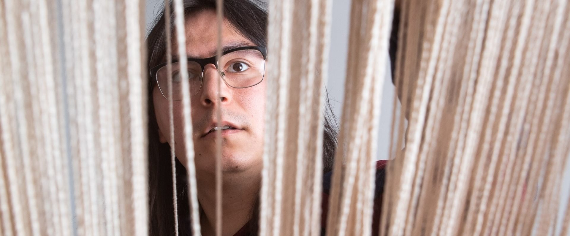 A person wearing glasses look up through vertical threads