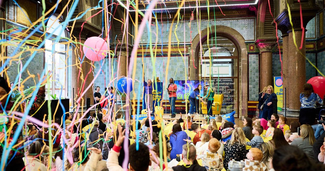 Read and Rave in Leeds Central Library. A crowd of people with party steamers and balloons.