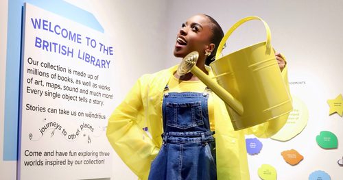 Amber Ogunsanya-William dressed with a yellow raincoat and wellies and holding a watering can.