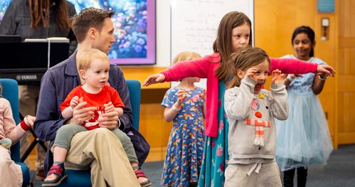 A family workshop taking place in the Library with children dancing