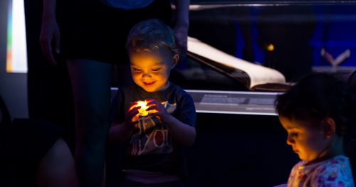 Toddler holding a battery powered tealight candle